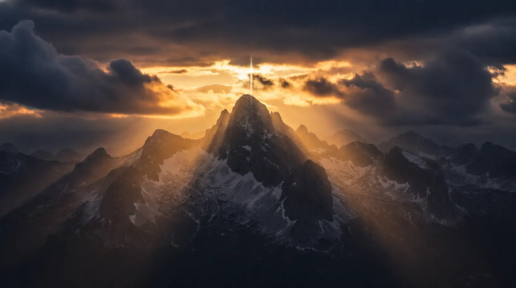 A cinematic sunrise over jagged mountain peaks, casting dramatic 'god rays' through the clouds into the deep valleys below. The lighting is majestic, moody, and ethereal, with deep blacks and vibrant gold sunlight creating a sense of divine presence.